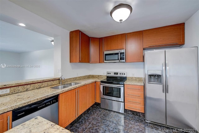 kitchen with stainless steel appliances, light stone countertops, and sink