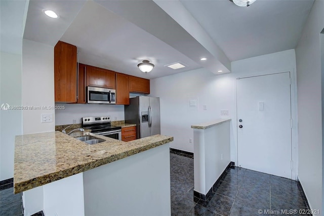 kitchen featuring appliances with stainless steel finishes, sink, dark tile patterned floors, light stone counters, and kitchen peninsula