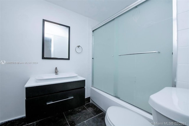 full bathroom with toilet, tile flooring, vanity, and bath / shower combo with glass door