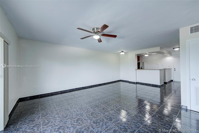 spare room featuring dark tile floors and ceiling fan