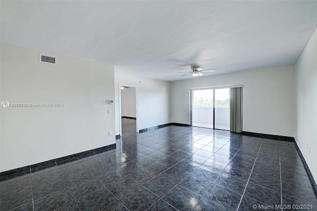 spare room featuring dark tile floors and ceiling fan