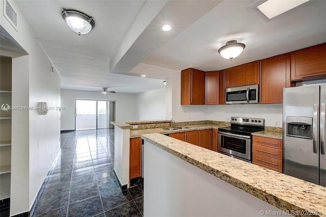 kitchen featuring kitchen peninsula, ceiling fan, sink, stainless steel appliances, and dark tile flooring