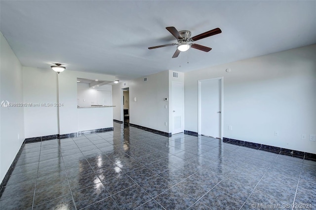 unfurnished room featuring dark tile floors and ceiling fan