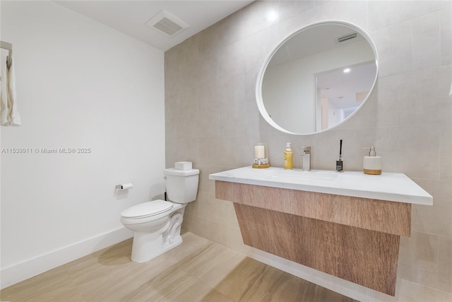 bathroom featuring tile walls, vanity, and toilet