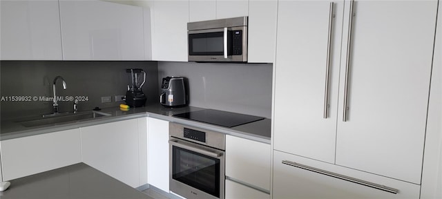 kitchen with white cabinetry, backsplash, sink, and stainless steel appliances