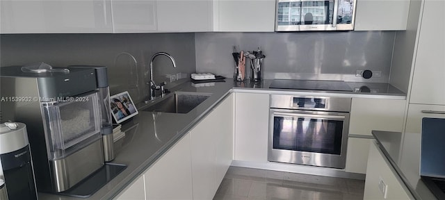 kitchen with backsplash, stainless steel appliances, white cabinetry, and sink