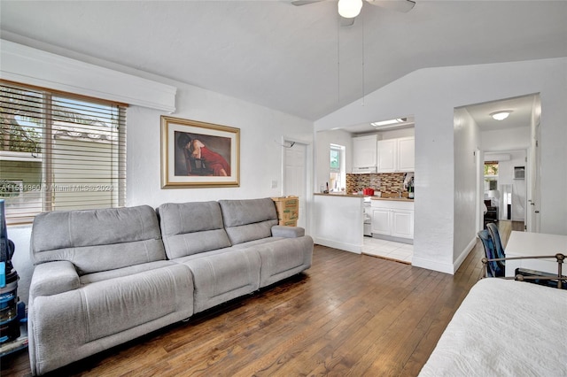 living room with ceiling fan, dark hardwood / wood-style floors, and vaulted ceiling