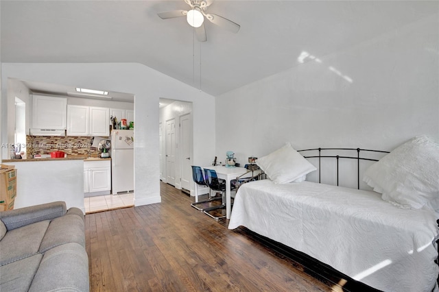 bedroom featuring white refrigerator, vaulted ceiling, wood-type flooring, and ceiling fan