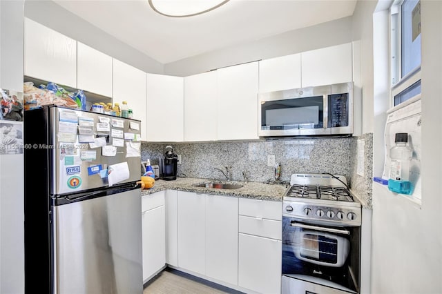 kitchen with white cabinets, sink, tasteful backsplash, and stainless steel appliances