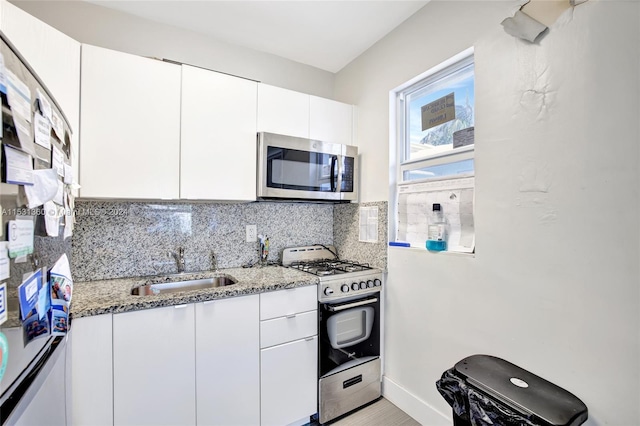 kitchen featuring white cabinetry, backsplash, light stone counters, sink, and range with gas cooktop