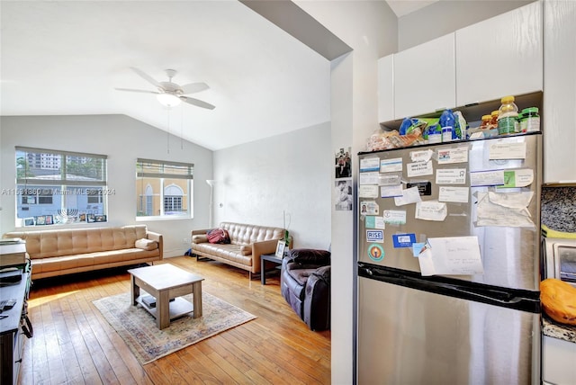 living room with light hardwood / wood-style floors, ceiling fan, and vaulted ceiling