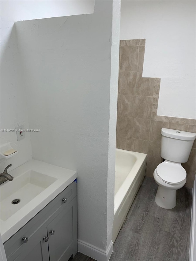 bathroom featuring vanity, hardwood / wood-style floors, toilet, and tile walls