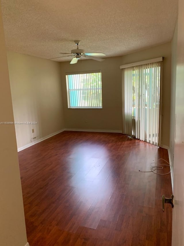 spare room featuring dark hardwood / wood-style floors, a textured ceiling, and ceiling fan