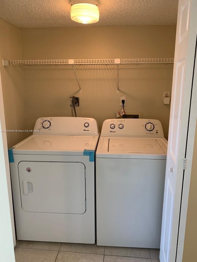 laundry room with light tile flooring, a textured ceiling, and independent washer and dryer