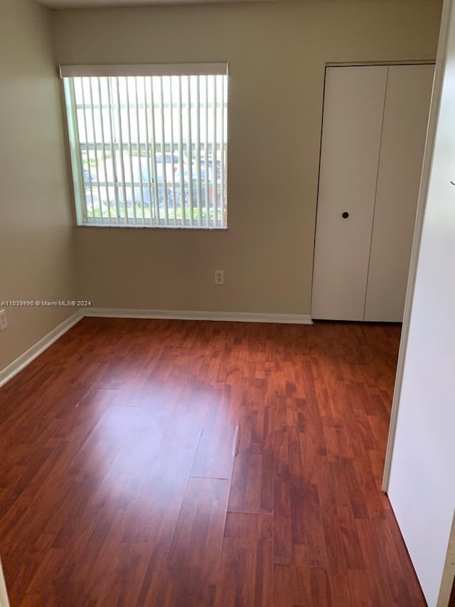 unfurnished bedroom featuring dark hardwood / wood-style flooring and a closet