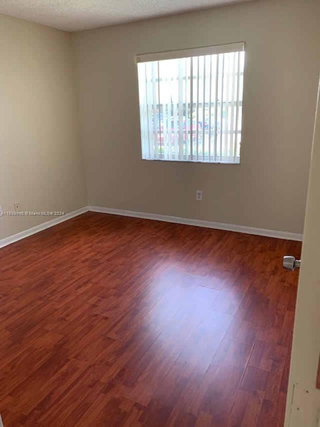 unfurnished room featuring a textured ceiling and dark wood-type flooring