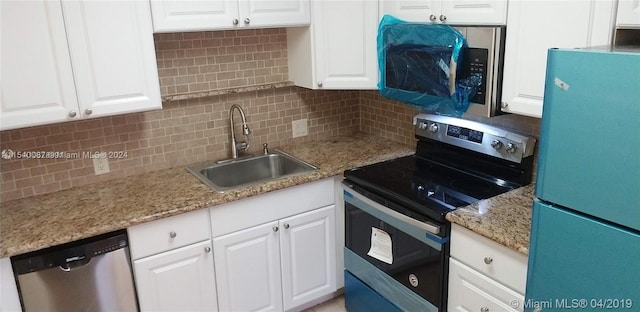 kitchen featuring stainless steel appliances, light stone countertops, tasteful backsplash, white cabinetry, and sink