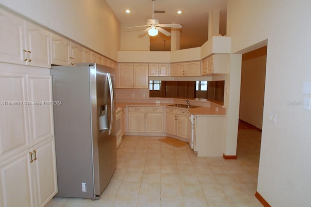 kitchen with range, ceiling fan, stainless steel fridge, light tile flooring, and high vaulted ceiling