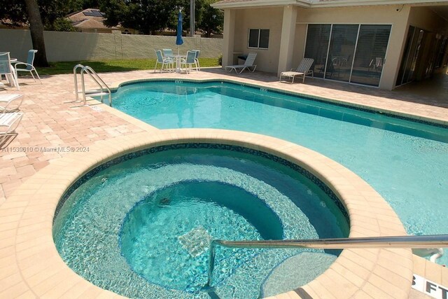 view of pool with a patio area and an in ground hot tub