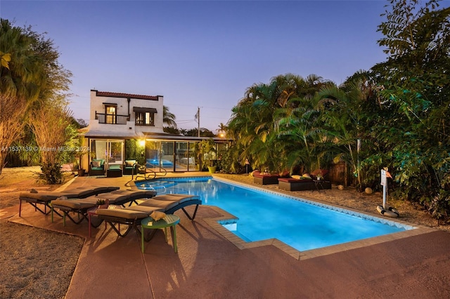 pool at dusk with a patio area