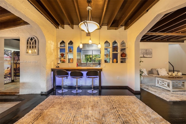 interior space with dark wood-type flooring, beam ceiling, and wooden ceiling