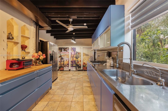 kitchen with beamed ceiling, stainless steel appliances, sink, light tile patterned floors, and butcher block countertops