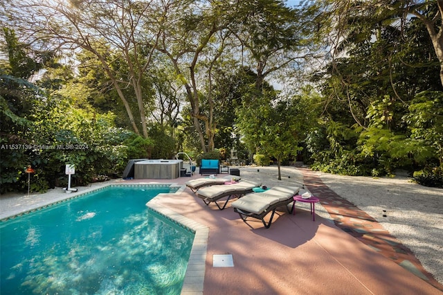 view of swimming pool featuring a patio and a hot tub