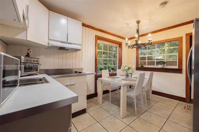 kitchen with light tile patterned flooring, decorative light fixtures, white cabinets, ornamental molding, and an inviting chandelier