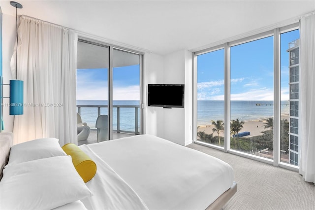 bedroom featuring light colored carpet, a view of the beach, access to exterior, floor to ceiling windows, and a water view