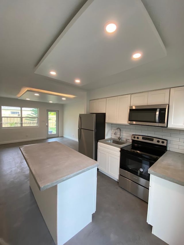 kitchen featuring white cabinetry, backsplash, appliances with stainless steel finishes, sink, and a center island