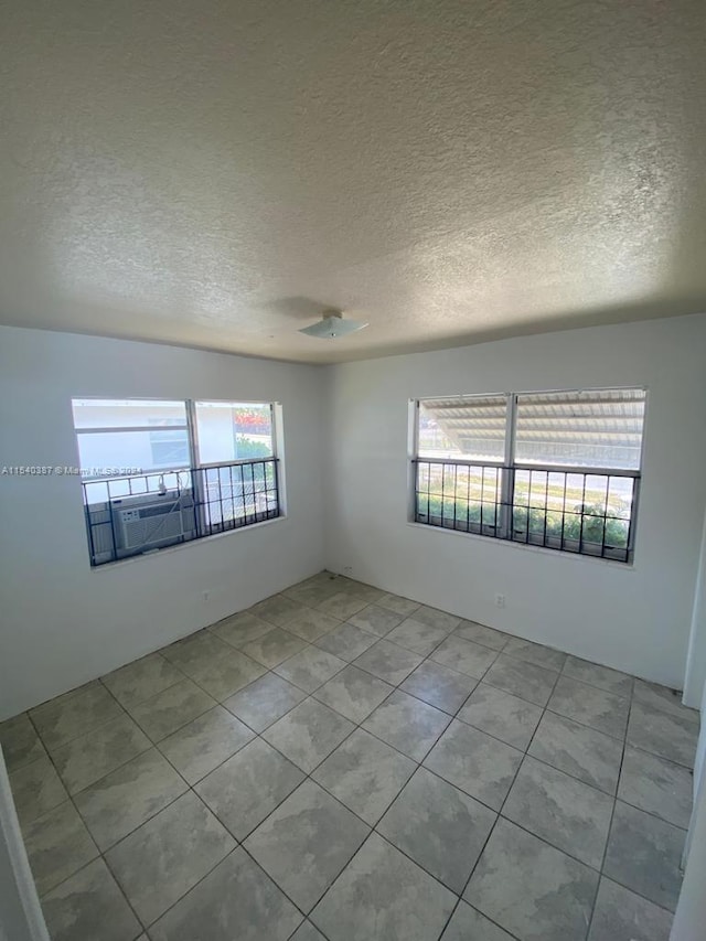 unfurnished room with a textured ceiling and light tile floors