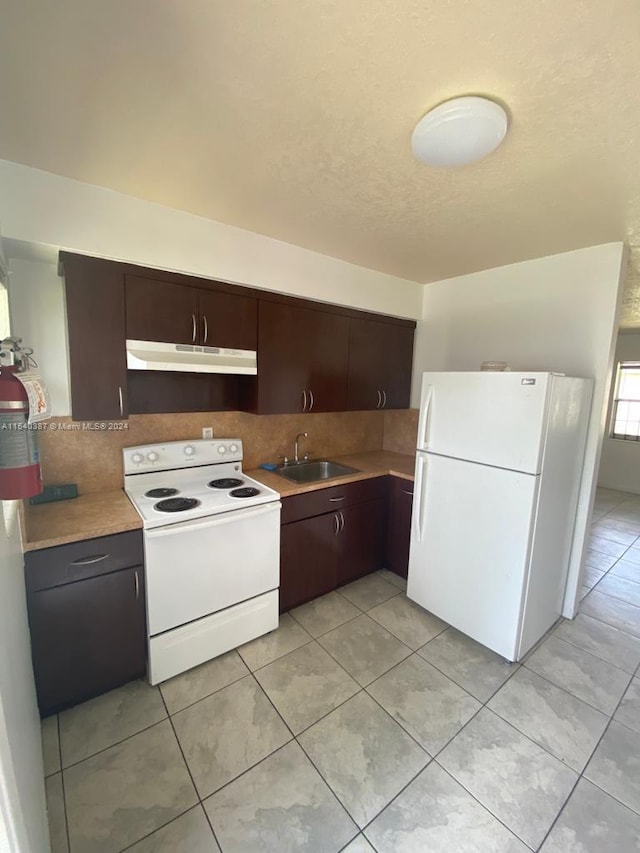 kitchen with dark brown cabinets, white appliances, light tile flooring, and sink