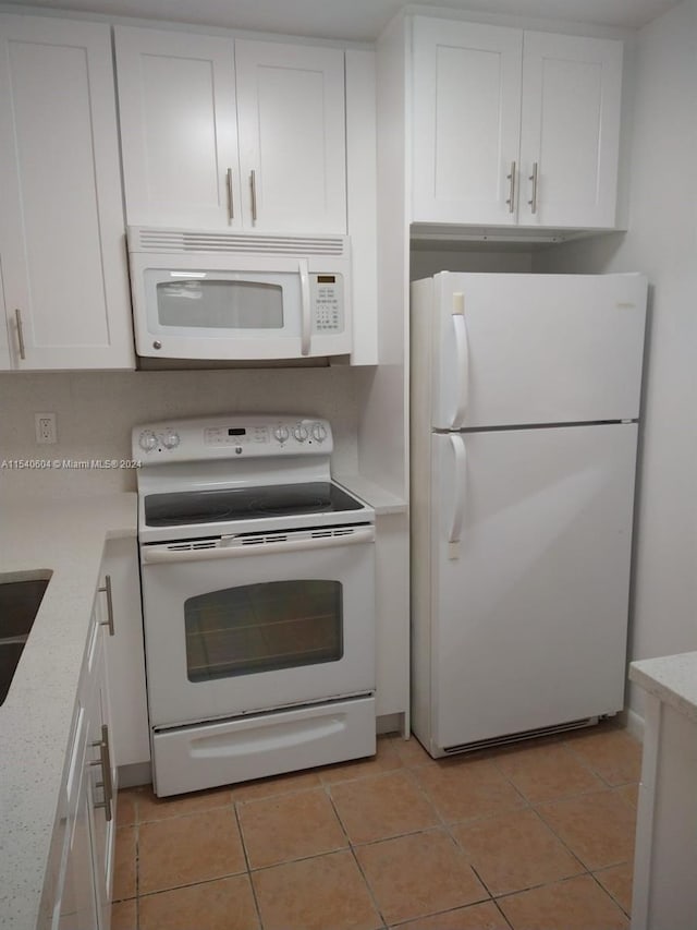 kitchen with light stone countertops, white appliances, light tile patterned flooring, and white cabinets