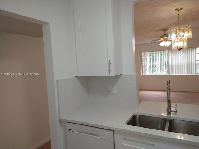 kitchen featuring sink, white dishwasher, light stone countertops, decorative light fixtures, and white cabinets