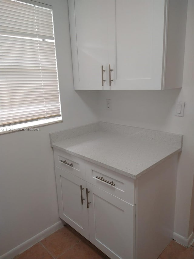 kitchen featuring tile patterned flooring, white cabinetry, and light stone counters