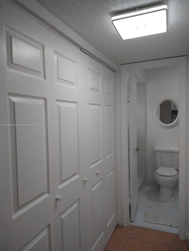 bathroom featuring tile patterned floors, toilet, and a textured ceiling