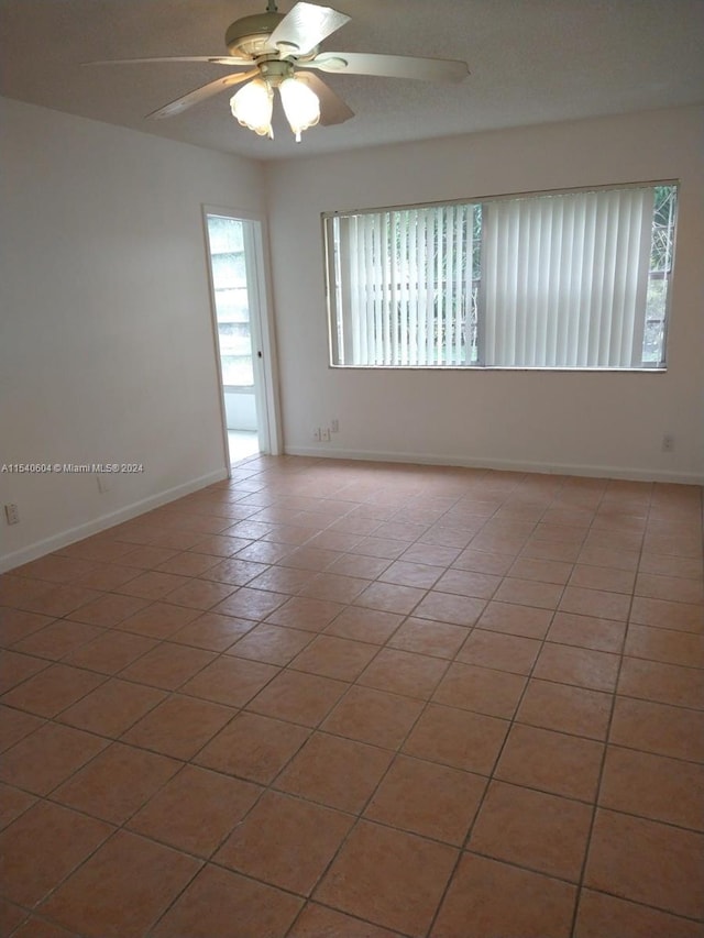 tiled spare room featuring ceiling fan