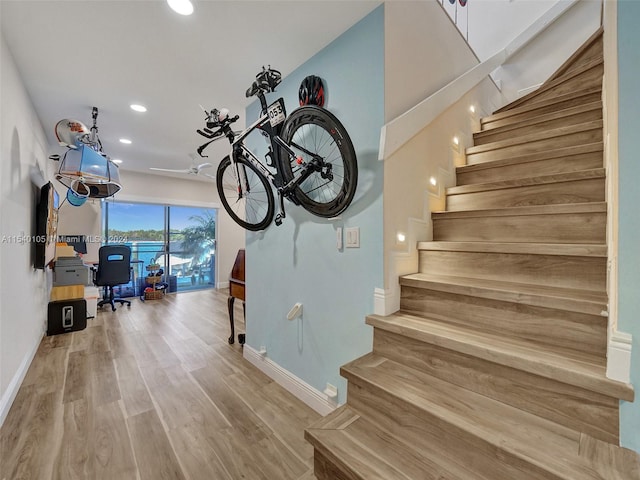 stairway with light hardwood / wood-style floors and ceiling fan