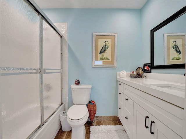 full bathroom with vanity, wood-type flooring, shower / bath combination with glass door, and toilet