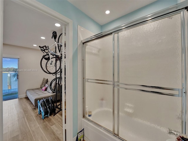 bathroom with combined bath / shower with glass door and hardwood / wood-style floors