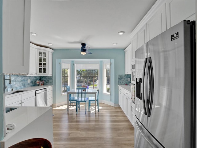 kitchen with white cabinets, tasteful backsplash, light hardwood / wood-style floors, and appliances with stainless steel finishes