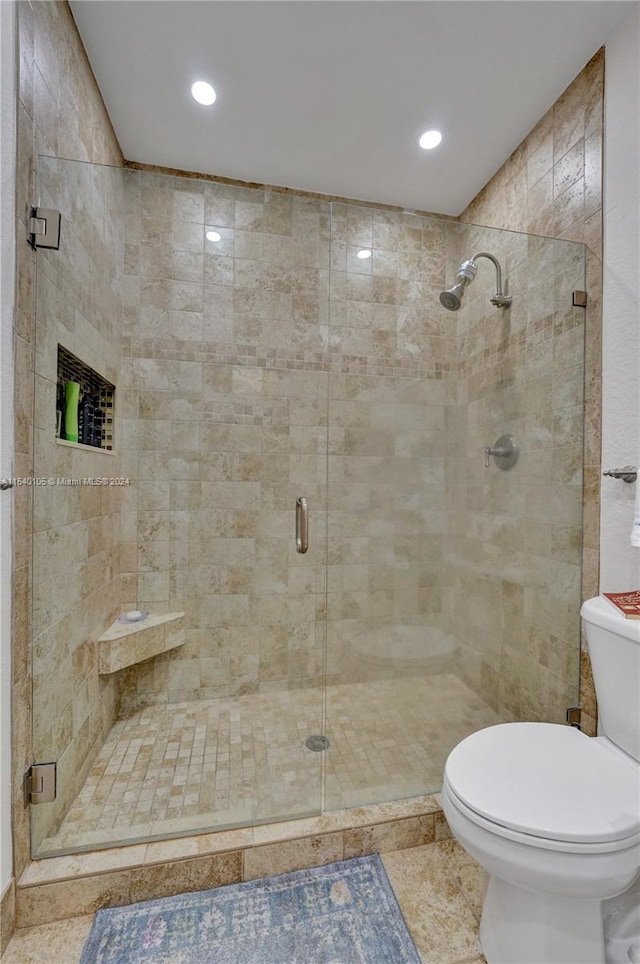 bathroom with a shower with door, tile floors, toilet, and tile walls