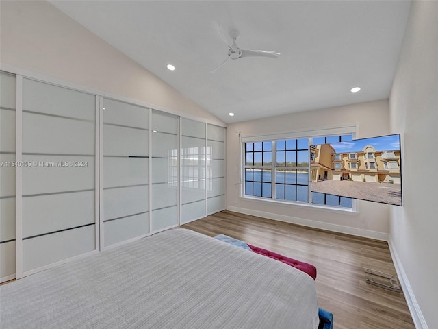 unfurnished bedroom with a water view, vaulted ceiling, light hardwood / wood-style floors, and ceiling fan