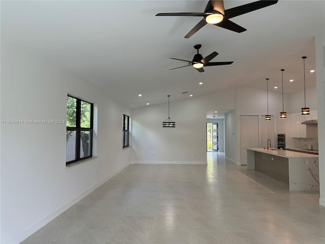 unfurnished living room featuring lofted ceiling, plenty of natural light, ceiling fan, and sink