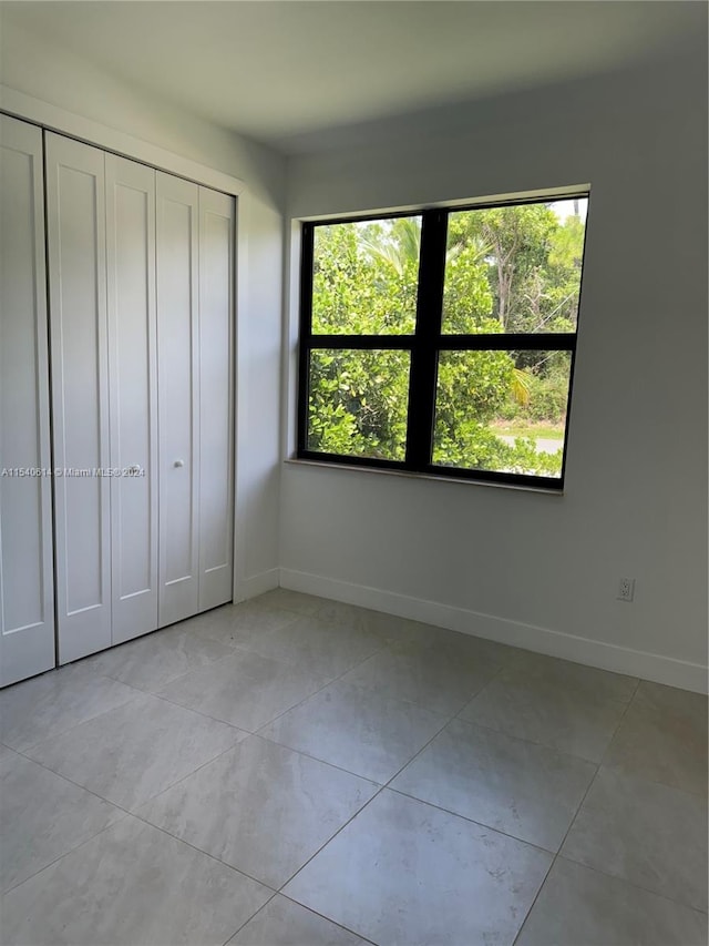 unfurnished bedroom with light tile patterned floors and a closet