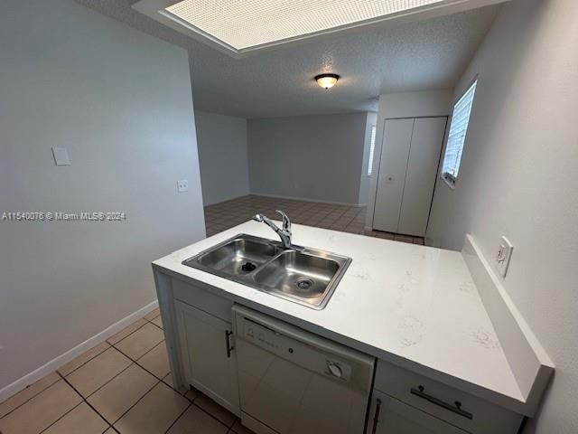 2626 SE 20th Ct Unit 206-B, Homestead, FL 33035 - kitchen featuring a textured ceiling, white dishwasher, gray cabinets, light tile patterned floors, and sink