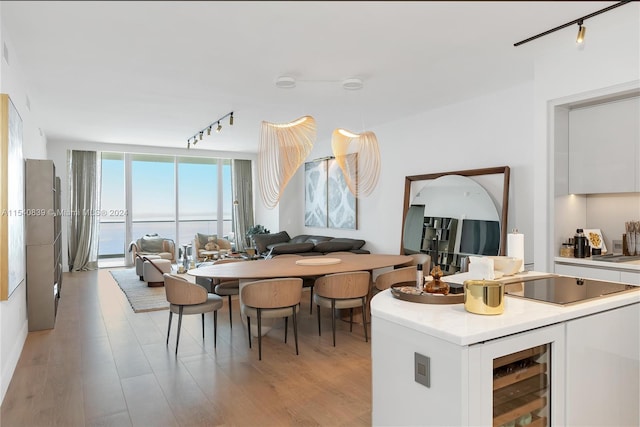 dining area featuring track lighting, bar, a water view, and light hardwood / wood-style flooring