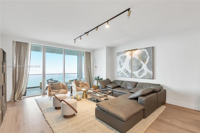 living room with a water view, light hardwood / wood-style flooring, and track lighting