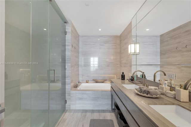 bathroom with dual vanity, tile flooring, independent shower and bath, and tile walls