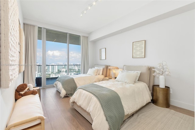 bedroom featuring rail lighting, access to outside, and light hardwood / wood-style flooring